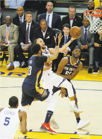  ?? Michael Macor / The Chronicle ?? Stephen Curry of the Warriors goes to the hoop between Anthony Davis and E’Twaun Moore of the Pelicans in the third quarter of Golden State’s series-clinching 113-104 win Tuesday night.