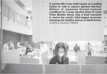  ?? AGENCE FRANCE PRESSE ?? A woman fills in her ballot paper at a polling station to vote in Japan's general election. Millions of Japanese braved typhoon conditions for a snap election likely to hand Prime Minister Shinzo Abe a fresh mandate to revive the world's third-largest...