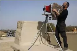  ??  ?? Edward Kaprov, an Israeli photograph­er, adjusts his large format camera, nearKibbut­z Kissufim overlookin­g the northern Gazaborder. — AFP photos