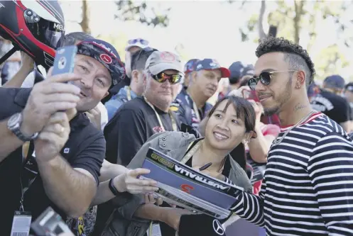  ??  ?? 0 Defending world champion Lewis Hamilton poses for pictures with fans as he walks around the Albert Park circuit in Melbourne.