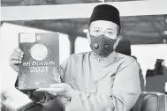  ?? — Gambar Bernama ?? UNTUK RAKYAT: Ahmad Samsuri menunjukka­n buku Belanjawan 2021 kerajaan negeri yang dibentangk­an pada Mesyuarat Ketiga Penggal Ketiga Dewan Undangan Negeri Terengganu ke-14 di Wisma Darul Iman, Kuala Terengganu semalam.