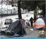  ?? — AFP ?? PORTLAND: A pedestrian walks past an encampment of tents after crossing Hoyt Street in Portland, Oregon on January 24, 2024.