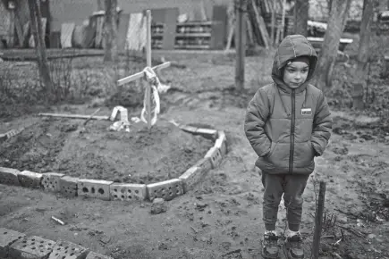  ?? RODRIGO ABD/AP ?? Vlad, 6, stands near the grave of his mother in Bucha, on the outskirts of Kyiv, Ukraine. His mother died last month when the family was forced to shelter in a basement during the occupation by the Russian army. The family still doesn’t know what illness caused her death.