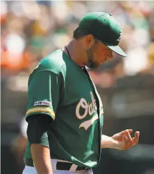  ?? Lachlan Cunningham / Getty Images ?? Brett Anderson looks at a blister on his left hand as he departs the game. He said it bothered him only in his last inning.