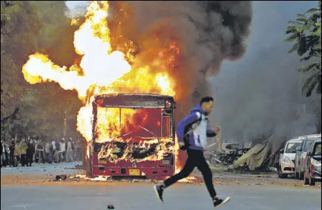  ?? REUTERS ?? A man runs past a bus that was set on fire by protesters near New Friends Colony in New Delhi on Sunday. >>P6