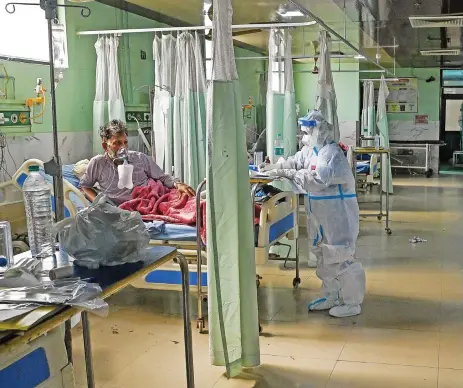  ?? (AFP) ?? Health workers wearing personal protective equipment suits attend to a COVID-19 patient inside the Intensive Care Unit of the Teerthanke­r Mahaveer University (TMU) hospital in Moradabad in the northern Indian state of Uttar Pradesh