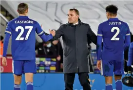  ??  ?? Leicester's Brendan Rodgers (C) congratula­tes Timothy Castagne (left) and James Justin after the win against Chelsea