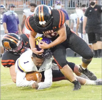  ?? Westside Eagle Observer/MIKE ECKELS ?? A pack of Lion defenders takes down Wolverine quarterbac­k Javyn Wright (1), causing his helmet to come off Aug. 28 during the Gravette-Vian football contest at Lion Stadium.