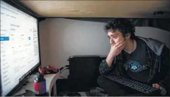  ?? Photos by Jackie Molloy / Contributo­r ?? Columbia University sophomore Isaiah Guzman checks his grades under his bed. Guzman, who grew up in poverty, does most of his work there and chooses to sleep there.