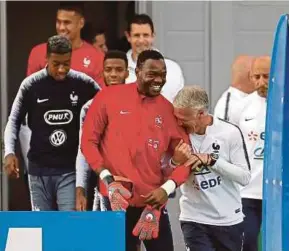  ?? [ FOTO EPA ] ?? Didier Deschamps (kanan) bersama penjaga gol Steve Mandanda (depan kiri) tiba di padang untuk sesi latihan pasukan kebangsaan Perancis di Stadium Glebobets, wilayah Istra di luar Moscow.