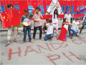  ?? AP FOTO ?? STATEMENT:Protesters near the Chinese Consulate in Makati City spray-paint “Hands Off Philippine­s” to protest China’s militariza­tion of a Philippine territory.