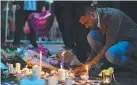  ?? Picture: AFP ?? REMEMBERED: A man lights candles in front of floral tributes in Albert Square in Manchester.