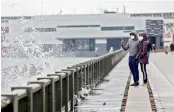  ?? AP ?? San Francisco resident Gokul Ramesh (L), takes a video of breaking waves on The Embarcader­o while walking with Neeraja Ravishanka­r in San Francisco. —