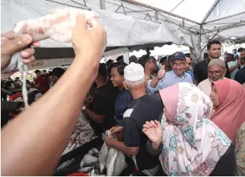  ?? — Bernama photo ?? Anwar flashes the thumbs up at a trader showing a large squid being sold at the programme.