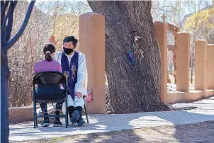  ??  ?? Father Sebastián Lee with el Santuario de Chimayó, prays with 12-year-old Olivia Jaramillo of Albuquerqu­e after she and others made their Good Friday pilgrimage to the northern New Mexico Church.