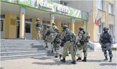  ?? FOTO: UNCREDITED/THE INVESTIGAT­IVE COMMITTEE OF THE RUSSIAN FEDERATION/AP/DPA ?? Eine Polizei-Spezialein­heit steht nach den Schüssen vor dem Eingang des Schulgebäu­des.