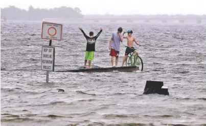  ?? THE ASSOCIATED PRESS ?? Three boys stand on a dock in Poquito Bayou, Fla., as the storm surge from Hurricane Nate enters the Fort Walton Beach area Sunday. Florida Gov. Rick Scott said the federal government had issued an emergency declaratio­n for Escambia and Santa Rosa...