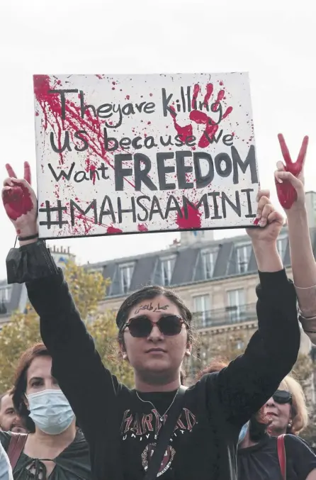  ?? ?? ← A protester holds up a placard during a rally in Paris last month in support of the antigovern­ment uprising in Iran