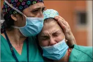  ?? MANU FERNANDEZ - THE ASSOCIATED PRESS ?? Health workers cry during a memorial for their co-worker Esteban, a male nurse that died of the coronaviru­s disease, at the Severo Ochoa Hospital in Leganes in Leganes, Spain, Friday, April 10. The new coronaviru­s causes mild or moderate symptoms for most people, but for some, especially older adults and people with existing health problems, it can cause more severe illness or death.