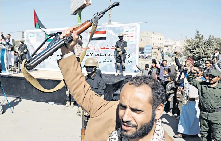  ?? ?? A man rises a rifle in the air as people in Sanaa, Yemen, gather to stage a protest against a UN resolution that demands the Houthis cease attacks on ships in the Red Sea