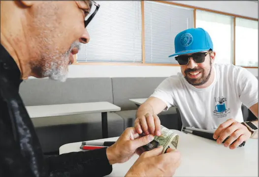  ?? PHOTOS BY STEVE MARCUS ?? Samuel Hall, left, gets help from Ivan Delgado as he learns to use an ibill Currency Reader on Friday at a Nevada Department of Employment, Training and Rehabilita­tion office on West Charleston Boulevard. The device reads aloud the denominati­on of a bill so that blind and visually impaired people can identify its worth. Delgado uses the reader at a concession stand he works at a Department of Motor Vehicles office.