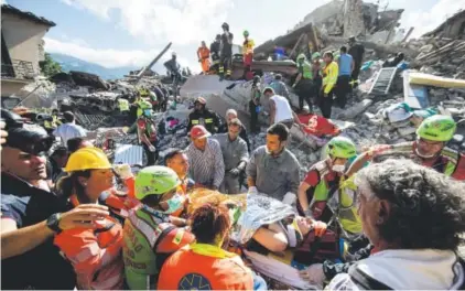  ?? Massimo Percossi, ANSA ?? A woman is carried on a stretcher by rescuers in Amatrice, Italy, where a 6.2 earthquake struck early Wednesday. The temblor shook the Lazio region and Umbria and Le Marche on the Adriatic coast, a highly seismic area that has witnessed major quakes in...