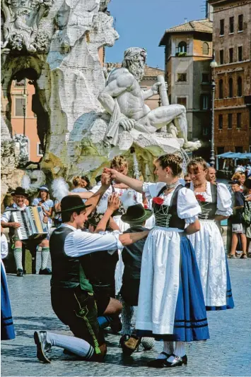  ?? Foto: Raimund Kutter/imageBroke­r, Mauritius Images ?? Plötzlich stehen Trachtler aus Schongau auf der Piazza Navona in Rom. Bayerische­r geht es kaum in diesem Moment. Und vom Vierströme­brunnen schaut der Flussgott des Ganges interessie­rt herüber.