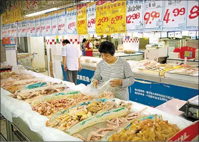  ?? AP/MARK SCHIEFELBE­IN ?? A woman browses the chicken section at a Beijing supermarke­t on Friday. As part of a new trade agreement, China will be allowed to send cooked poultry to the U.S.