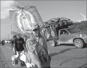  ?? AP Photo/Rebecca Blackwell ?? Journey: Erlin Troches, a 43-year-old Honduran migrant from the city of Santa Barbara, carries an image of the Virgin of Guadalupe that was given to him by a priest in southern Mexico, as he walks along with a thousands-strong caravan of Central Americans hoping to reach the U.S. border moves, outside Juchitan, Oaxaca state, Mexico on Thursday. Troches plans to carry the religious icon with him on the entire journey, saying she symbolizes "trust, faith, and hope" that he will make it to the U.S. border.