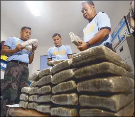  ?? MIGUEL DE GUZMAN ?? Police officers check marijuana bricks valued at P15 million confiscate­d from two women during a drug bust in Meycauyan, Bulacan on Thursday.