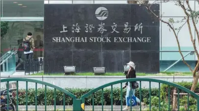  ?? WANG GANG / FOR CHINA DAILY Left: ?? Above: A pedestrian passes the Shanghai Stock Exchange in Pudong New Area.