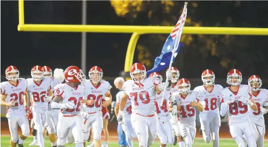  ?? RICK KINTZEL/THE MORNING CALL ?? Easton’s Albert Gayle (70) carries a flag with his teammates before the Red Rovers’ 2018 game against Freedom.