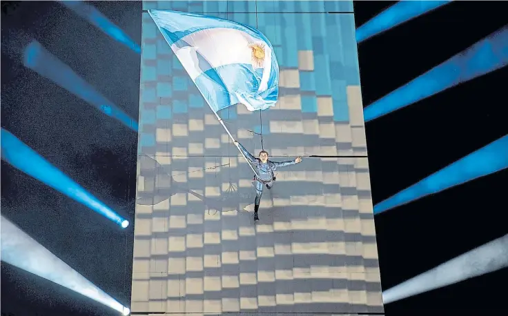  ?? REUTERS ?? Por el aire. La bandera de Argentina flamea por una de las paredes del Obelisco, en una de las escenas más sorprenden­tes del show de la ceremonia de apertura.