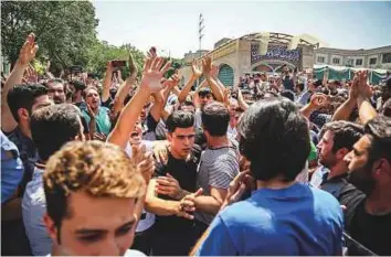  ?? AP ?? A group of protesters chant slogans at the main gate of the Grand Bazaar in Tehran. Protesters forced shopkeeper­s to close their stalls, apparently angry over the country’s economy.