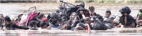  ?? AP ?? A new group of Central American migrants wade in mass across the Suchiate River, that connects Guatemala and Mexico, in Tecun Uman, Guatemala, on October 29, 2018. The first group was able to cross the river on rafts, an option now blocked by Mexican Navy river and shore patrols.
