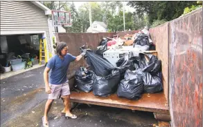  ??  ?? Nelson Magtangob, of Renwick Drive in Bridgeport, tosses trash into a Dumpster on Thursday after recent flooding.