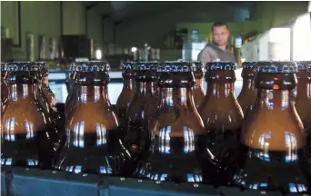  ??  ?? Bottles of freshly bottled beer stand in the Darling Brewery in Darling, South Africa. Darling is the first in Africa to go carbon-neutral. — IC