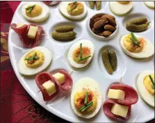  ?? (Arkansas Democrat-Gazette/Kelly Brant) ?? Deviled eggs alongside cornichons (tiny sour pickles), almonds and salami-wrapped cheese make an easy, yet festive finger food spread.