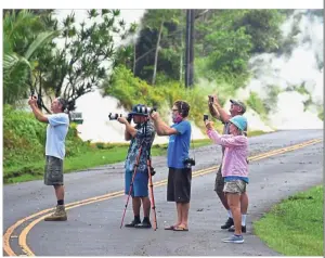  ??  ?? Nature shot: People taking photos of lava as steam rises from fissures on the road in Leilani Estates. — AFP