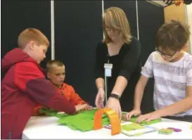  ?? ZACH SRNIS — THE MORNING JOURNAL ?? Sam Cawrse, 7, a second grader, left, Noah Cawrse, 9, a fourth grader, middle, and Grant Brown, 10, a fourth grader, all from Vermilion, work with Bethany Schmitkons to create a path for a robot.