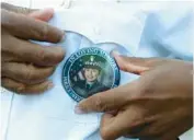  ?? JOHN J. KIM/CHICAGO TRIBUNE ?? Fifth District Commander Glenn White puts on a button with a photograph of Officer Ella French during a prayer service in her memory, outside the 22nd District, 1900 W. Monterey Ave., on Aug. 11, 2021, in Chicago.