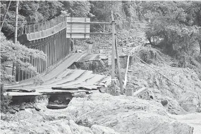  ?? — Gambar AFP ?? MUSNAH: Sebatang jalan terputus akibat banjir dan tanah runtuh yang dicetuskan hujan lebat dekat sungai Kuma di Ashikita, Kumamoto semalam.