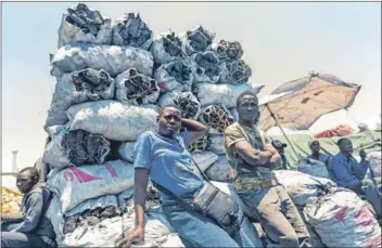  ??  ?? In demand: Prudence Mkonyo (centre) and other vendors are selling 50kg bags of charcoal in Mbare Musika market in Harare. Photo: Jekesai Njikizana/afp