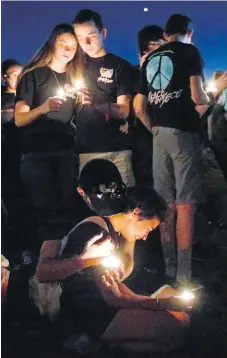  ?? WILFREDO LEE. THE ASSOCIATED PRESS ?? Students comfort each other at a candleligh­t vigil for the victims of Wednesday’s massacre at Marjory Stoneman Douglas High School in Parkland, Florida.