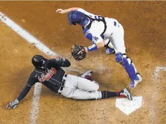  ?? David J. Phillip / Associated Press ?? Atlanta’s Nick Markakis scores past Dodgers catcher Will Smith on a double by Cristian Pache in the fifth inning. Los Angeles scored seven runs in the final three innings but fell short.