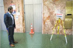  ?? Santiago Mejia / The Chronicle ?? Max Szabo of the district attorney's office stands near an out-of-order elevator at the Hall of Justice. The Board of Supervisor­s votes Tuesday on measures that would clear the way to move workers out of the building.