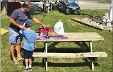  ?? CHAD FELTON — THE NEWS-HERALD ?? Art Carina, past commodore of Mentor Lagoons Yacht Club, presents prizes to a young fisherman on Aug. 28during Mentor PerchFest.