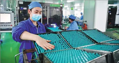  ?? FENG DAPENG / XINHUA ?? Employees check medicines before they are packed at a pharmaceut­ical company in Nanyang, Henan province, in February.