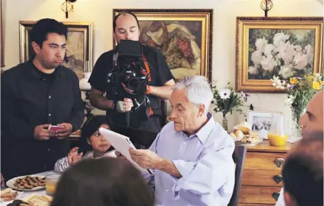  ??  ?? O Sebastián Piñera durante el rodaje de su franja, compartien­do la mesa con una familia chilena.