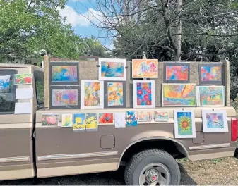  ?? Photos courtesy of Blair Chandler ?? Watercolor art by Boulder- based artist Blair Chandler is displayed on a pickup in front of her home. Blair and husband Peter Chandler, a wood carver, have been hosting weekly art pop- ups in their yard and on a large fence on the property.